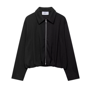 Close-up of black pleated velvet bomber jacket showing soft fabric texture and zipper