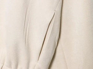 Détail de la couture de poche sur la veste de baseball en daim beige au fini doux