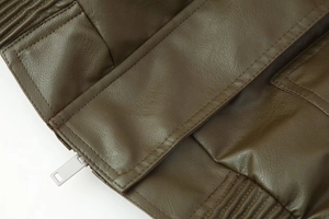 Détail d'une veste en similicuir vert olive foncé avec coutures fines et zip métallique argent