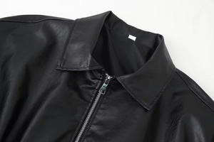 Detail einer schwarzen Vintage-Lederjacke mit Reverskragen und silbernem Metall-Reißverschluss