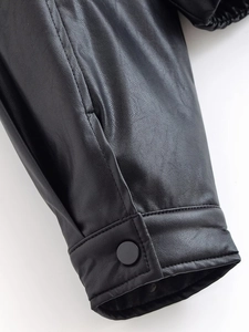 Detail of black faux leather jacket cuff with matte finish and button closure