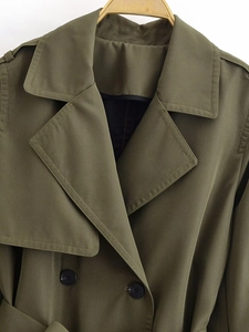 Close-up of olive green double-breasted trench coat with notched lapels and shoulder epaulets