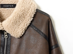 Detail of faux leather jacket featuring white shearling collar and silver metal zipper
