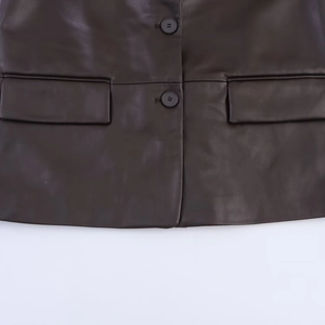 Detail view of deep brown faux leather jacket with symmetrical pocket flaps and black buttons