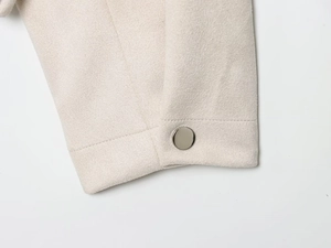 Gros plan du poignet avec bouton métallique sur une veste baseball beige