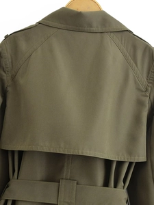 Detail of olive green trench coat storm flap and raglan sleeve with waist belt