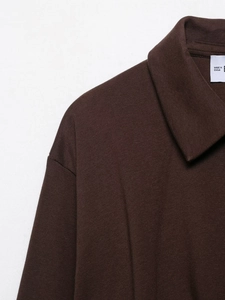 Detail of a dark brown pleated velvet flight jacket collar with precise stitching and label