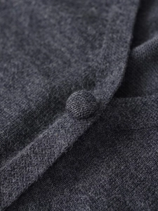 Macro detail of charcoal grey knit cardigan featuring matching fabric-covered buttons