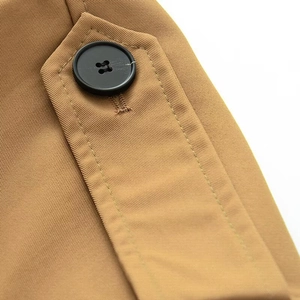 Détail macro de l'épaulette d'un trench-coat kaki avec bouton et texture de sergé