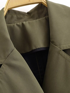 Detail view of olive green double-breasted coat featuring twill texture and classic lapels