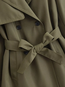 Detailed view of olive green double-breasted trench coat with tied waist belt