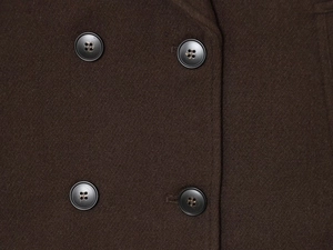 Macro shot of dark brown double-breasted coat with thick twill wool texture and black buttons