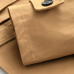 Vue macro montrant la texture du tissu sergé et les coutures du manteau kaki