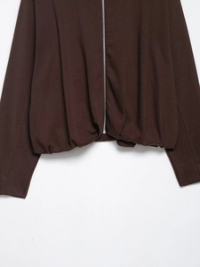 Detail of dark brown velvet bomber jacket with silver metal zipper and pleated hem