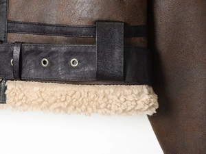 Macro detail of brown faux leather jacket with metal eyelets and beige shearling lining