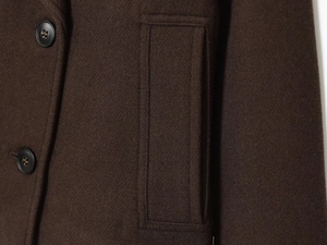 Macro detail of dark brown twill wool fabric with round buttons and flat pocket stitching