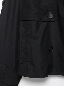 Détails macro du tissu sergé du trench-coat noir avec bouton et poche à rabat