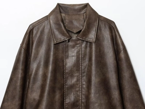 Detail of deep brown PU jacket featuring lapel collar, stitching, and textured faux leather
