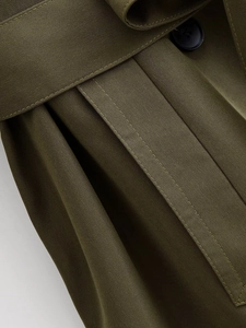 Detail of army green trench coat featuring double stitching, belt, and resin button