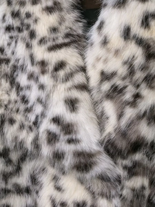 Close-up detail of soft faux fur fabric with black and white leopard animal print pattern