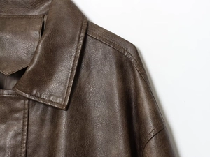 Detailed view of dark brown PU leather texture and lapel stitching on long jacket