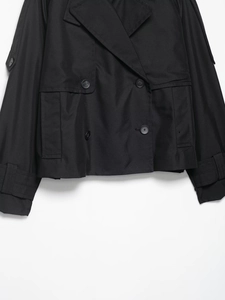 Détail des boutons croisés et épaulettes sur une veste trench courte de couleur noire