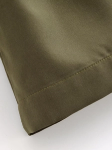 Detailed macro shot of fine stitching and olive green fabric on the double-breasted coat