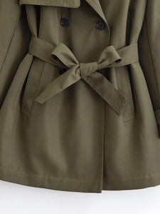 Detailed close-up of double-breasted olive trench coat with tied bow waist belt