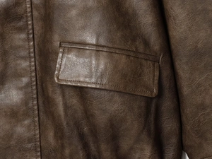 Close-up of brown PU leather jacket with vintage texture and detailed flap pocket stitching