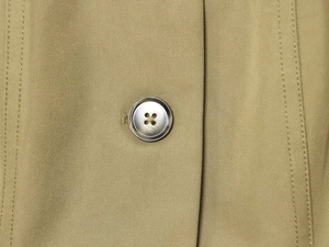 Macro detail of the silver button and premium twill fabric on the khaki jacket