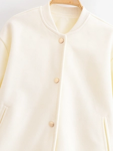 Close-up of cream bomber jacket showing ribbed collar and golden snap buttons