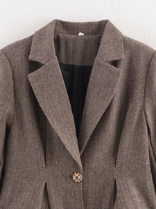 Detail of brown herringbone wool blazer showing notch lapel and textured fabric