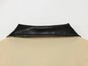 Détail du col en cuir noir cousu sur une veste de travail en grosse toile beige