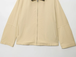 Détail d'une veste en toile kaki avec fermeture éclair en métal et poches latérales