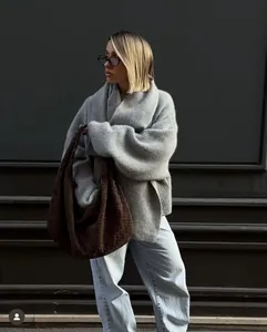 Detail view of grey chunky rib knit sweater with oversized collar and woven texture bag
