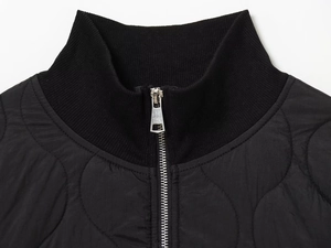 Detail of black onion-quilted jacket featuring ribbed stand collar and silver metal zipper