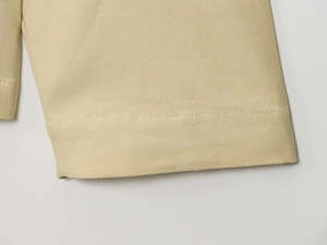 Vue macro des coutures précises sur la manche de veste en toile beige et texture du tissu