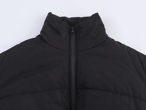 Gros plan du col montant et de la texture matelassée mate de la veste d'hiver noire
