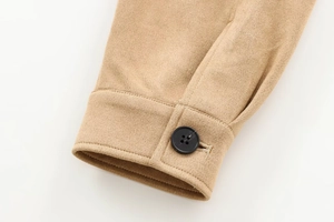 Détail de la manche d'une veste en daim camel avec un bouton noir et une couture fine