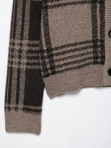 Gros plan du tissu de cardigan en tricot écossais marron avec poignets côtelés et bouton