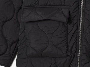 Detailed close-up of wavy quilted texture on a black jacket with a silver metal zipper