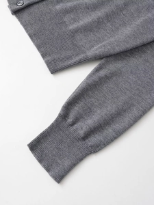 Detail of medium grey knit cardigan showing rib-knit cuffs and dark grey button