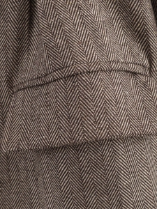 Macro view of brown herringbone wool fabric texture on a tailored blazer pocket