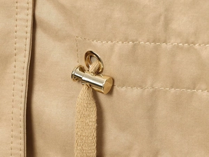 Macro shot of khaki cotton fabric with golden metal toggle and flat drawstring detail