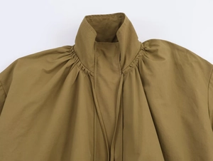Detail view of khaki bomber jacket featuring a high collar and pleated shoulder seams
