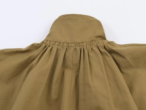 Detailed close-up of the gathered neckline and ruched stitching on earth-tone bomber jacket