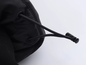 Détail du cordon de serrage noir avec oeillet métallique mat et boucle de réglage en plastique