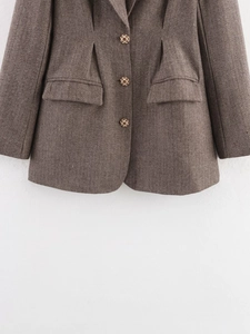 Detail of dark brown herringbone blazer with woven buttons and flap pockets close-up