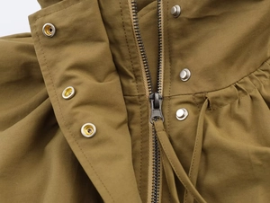 Detail of khaki bomber jacket featuring metal zipper, silver snaps, and drawstring collar