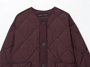 Close-up of diamond quilted burgundy jacket with black buttons and round neckline